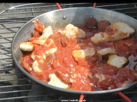 Adding chopped tomatoes and garlic to paella