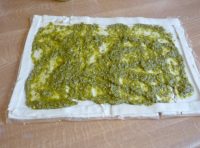 Pesto spread over uncooked puff pastry