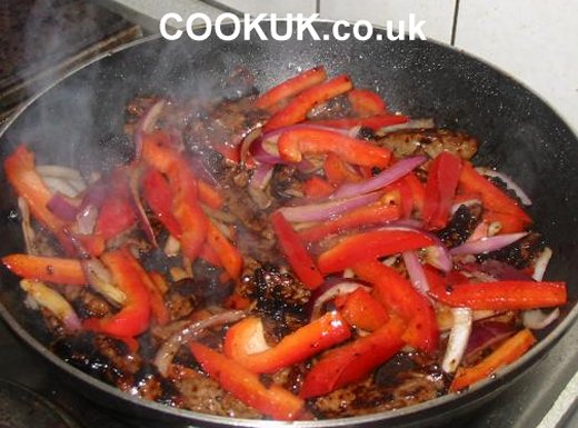 Sliced pepper and onions added to beef stir fry