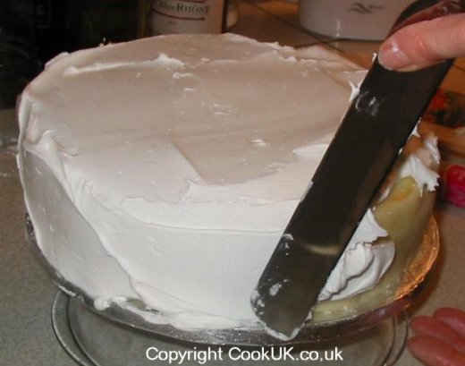 Smoothing traditional icing on sides of a Christmas cake