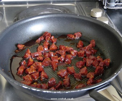Chorizo chunks frying in a pan