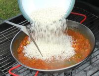Adding rice to seafood paella