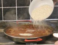 Adding rice to vegetable paella
