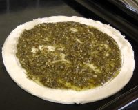 Pesto spread on uncooked puff pastry